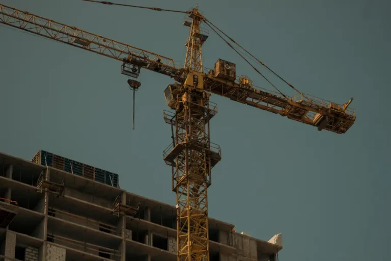 Tower crane beside a commercial building with a glass facade