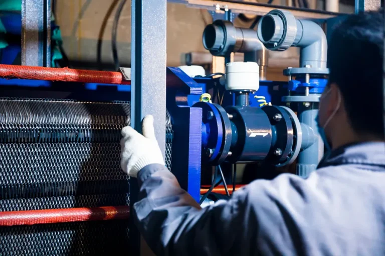 Technician inspecting pipework and equipment at an industrial plant